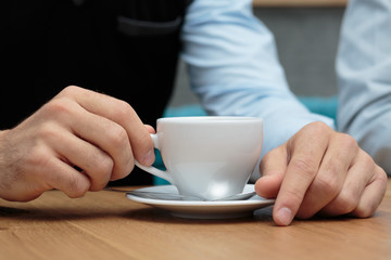 Junger Mann hält Kaffeetasse auf Holztisch