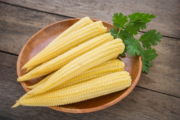 Fresh baby corn on wooden plate