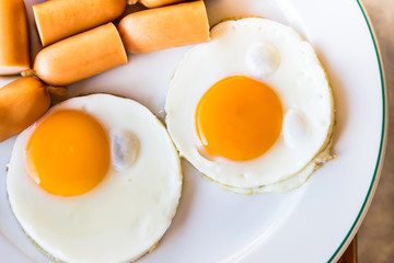 fried eggs and sausages on white plate