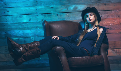 Cowgirl Wearing blue jeans and brown hat. Sitting on leather cha