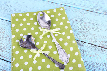 Metal spoons on green polka dot napkin on wooden background