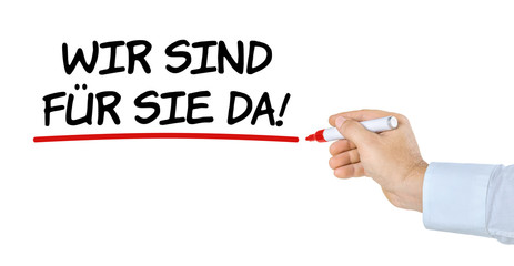 Hand mit Stift schreibt Wir sind für Sie da
