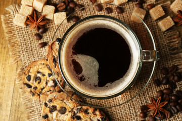 Glass cup of coffee and tasty cookie on wooden background