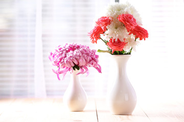 Beautiful flowers in vases with light from window