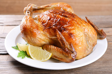 Delicious baked chicken on plate on table close-up
