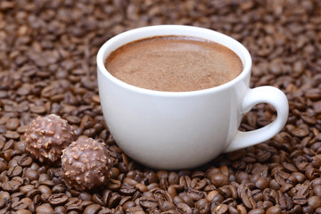Obraz premium cup of coffee and candies on a coffee beans background