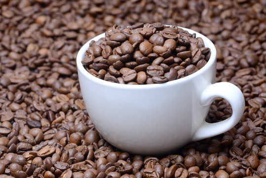 cup with coffee grains on a coffee beans background