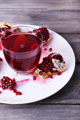 Ripe pomegranate and glass of juice on wooden table