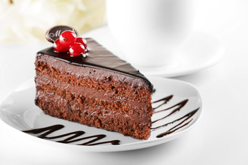 Delicious chocolate cake on plate on table on light background