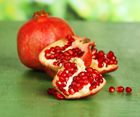 Juicy ripe pomegranates on green wooden table