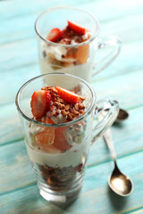 Healthy layered dessert with muesli and strawberries on table