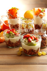 Healthy layered desserts with muesli and fruits on table