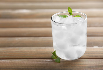 Glass with ice cubes on wooden table