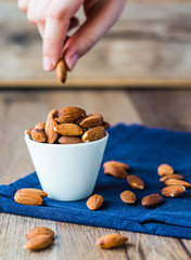 eat nuts, almonds hands of white cup