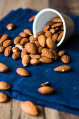 scatter nuts almonds in a white bowl on blue napkin