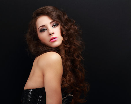 Beautiful makeup woman with brown long curly hair on black