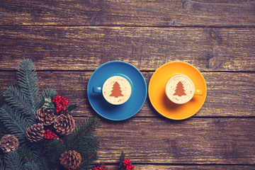 Two cups with christmas tree shape near branch on a wooden table