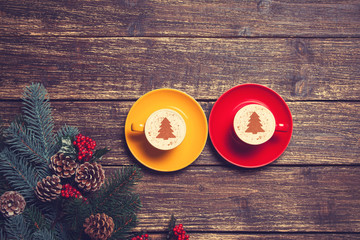 Two cups with christmas tree shape near branch on a wooden table