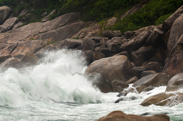 Wave crashing against stones at the rocky beach - power of natur