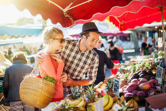a young couple buying fruits and vegetables at a market