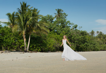 Fototapeta na wymiar Beautiful woman in white long dress runs at the beach