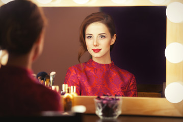 Beautiful redhead women appling makeup near mirror