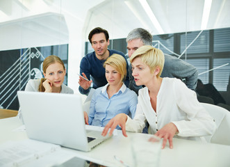 Team im Büro schaut auf Bildschirm von Laptop