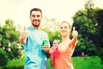 smiling couple with bottles of water outdoors