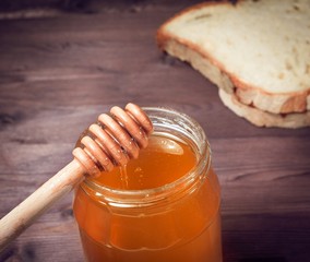 honey jar on wood table with wooden dipper on top