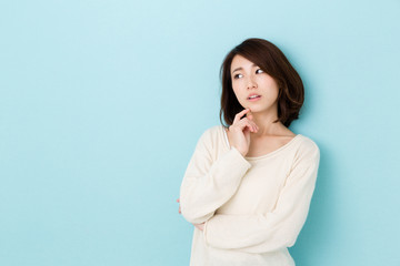 attractive asian woman thinking on blue background