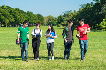 Happy group of students walking and talking at the park