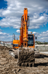 Big orange excavator against the blue sky