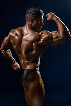 Handsome muscular bodybuilder posing over blue background