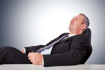 Happy man sitting at desk and leans back