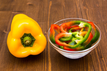 Pepper slices on bowl on wooden table
