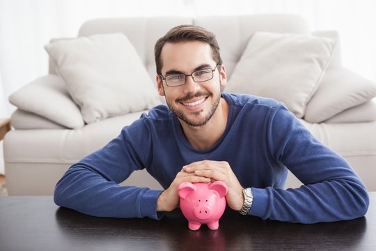 Smiling young man with piggy bank