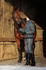 Pretty girl with her horse in stable door