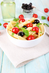 Pasta with tomatoes, olives and basil leaves in bowl