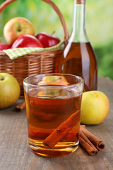Apple cider in glass and bottle, with cinnamon sticks and fresh