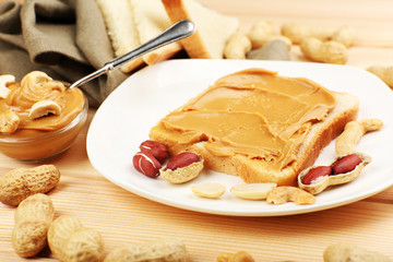Bread slices with creamy peanut butter on wooden table