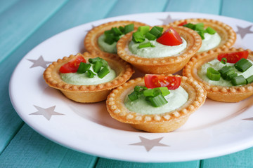 Tartlets with greens and vegetables with sauce on plate on