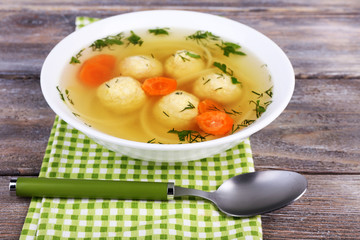 Soup with meatballs and noodles in bowl on wooden background