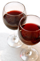 two glasses with red wine standing on table-cloth