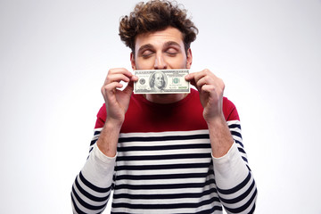 Happy man kissing dollar bill over gray background