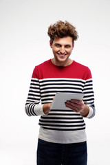 Cheerful casual man using tablet computer over gray background