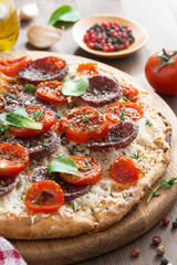 Italian food - pizza with salami and tomatoes on board, vertical