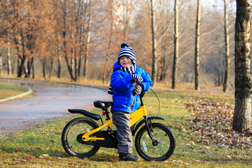 Fototapeta na wymiar happy little boy with bike in autumn park