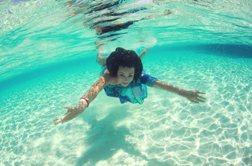 Lovely woman wearing dress and swimming in the ocean