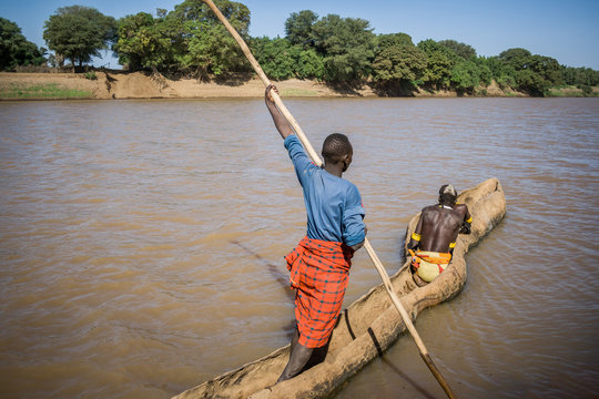 Men cross the Omo River near Turmi using a wooden boat, Ethiopia