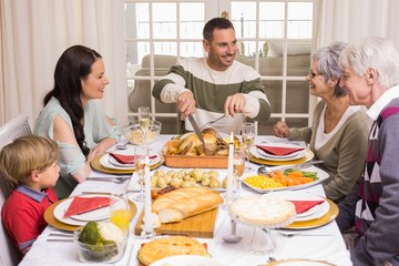 Man carving chicken during christmas dinner